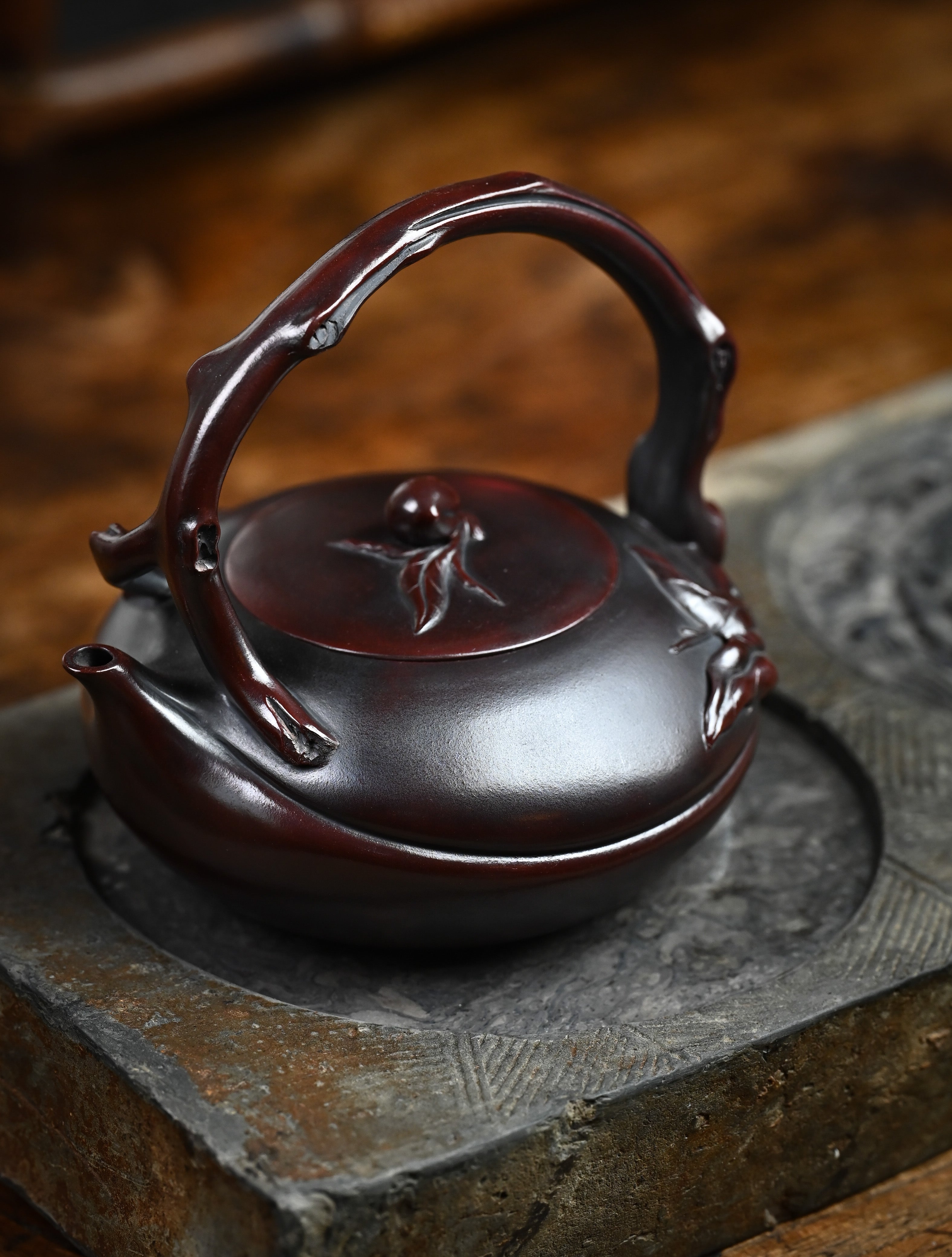 YANYOO handmade Yixing teapot featuring aged Wuni clay, lifting handle and peach sculpture, lifestyle left side.