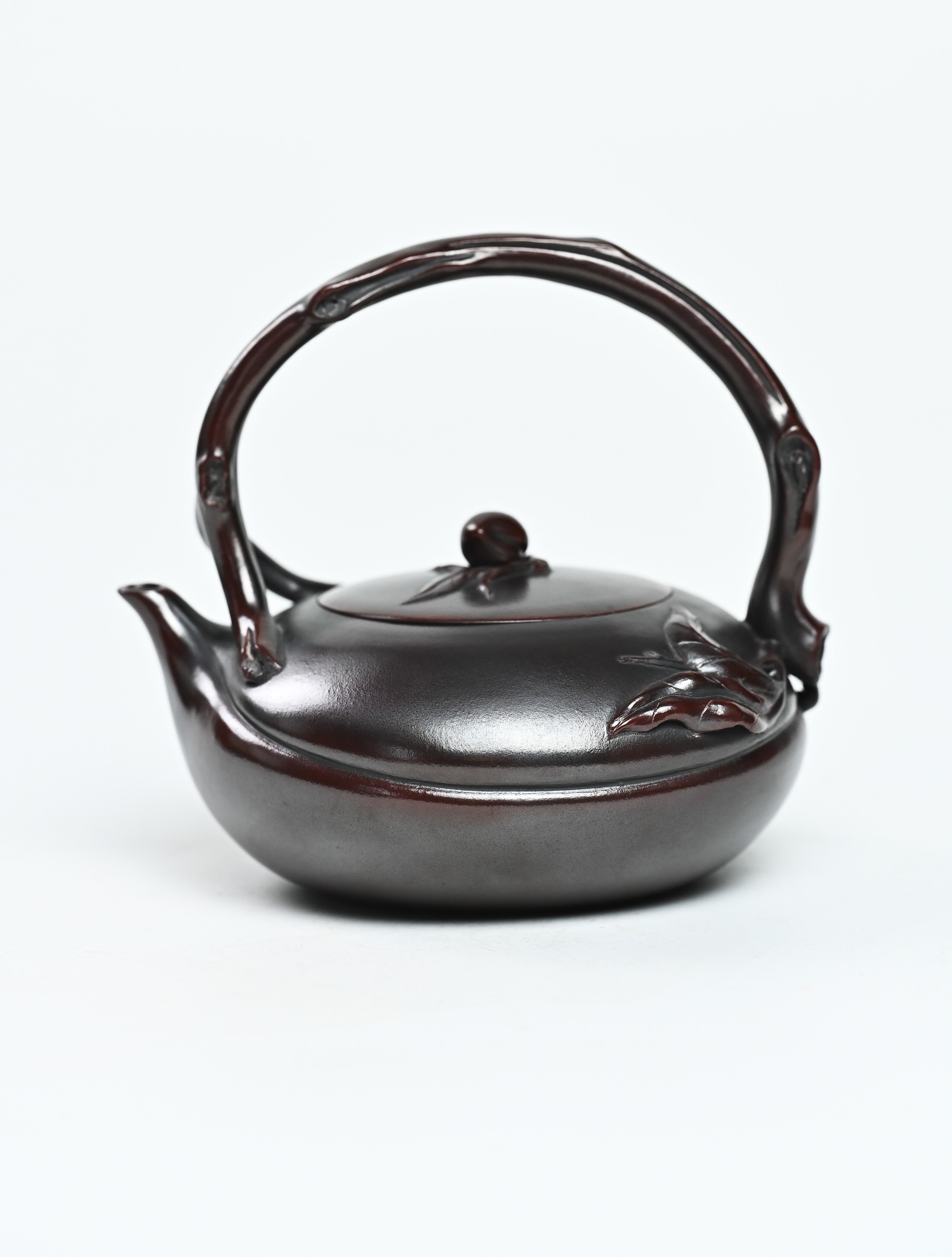 YANYOO handmade Yixing teapot featuring aged Wuni clay, lifting handle and peach sculpture, product left side.