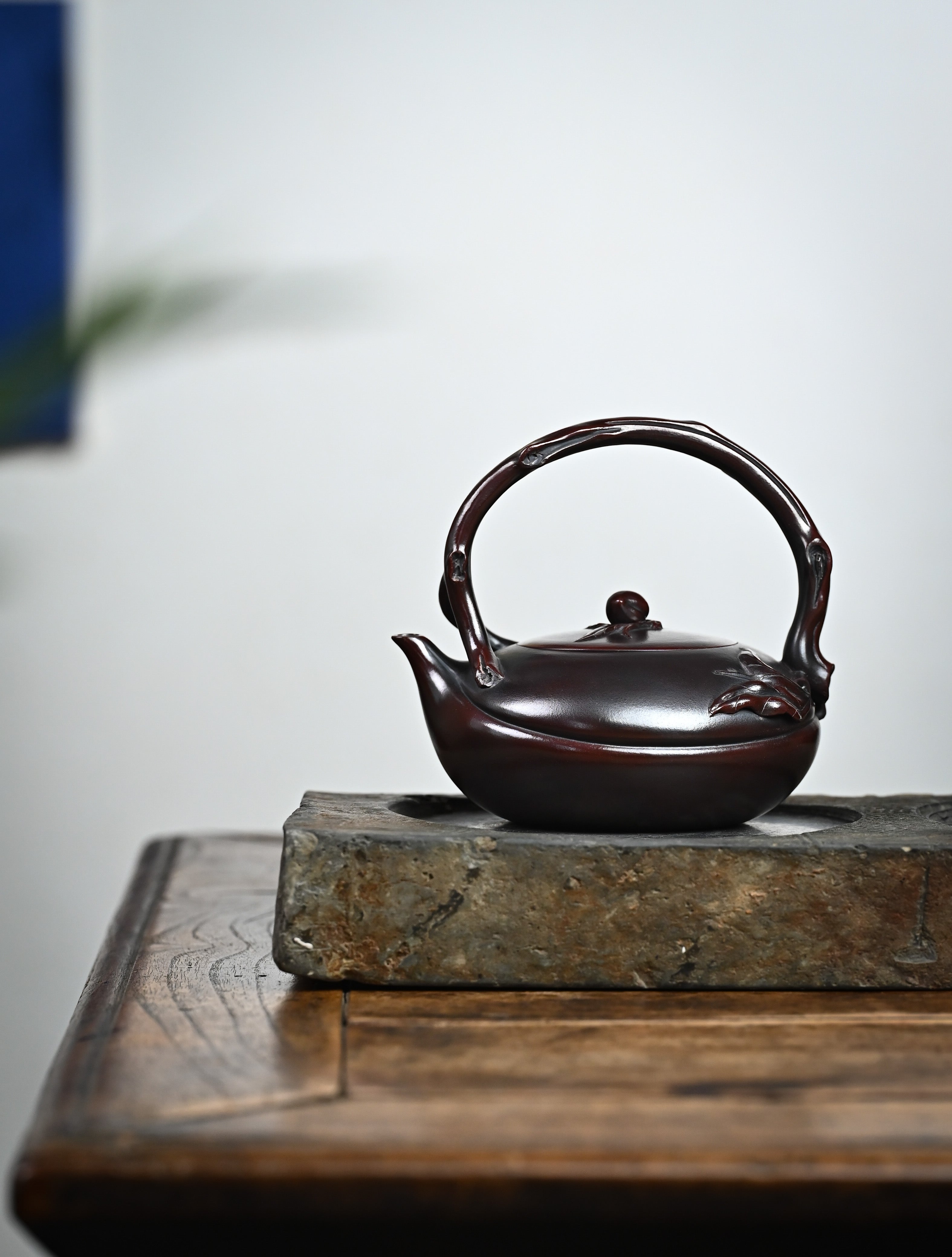 YANYOO handmade Yixing teapot featuring aged Wuni clay, lifting handle and peach sculpture, lifestyle wide-angle left side.