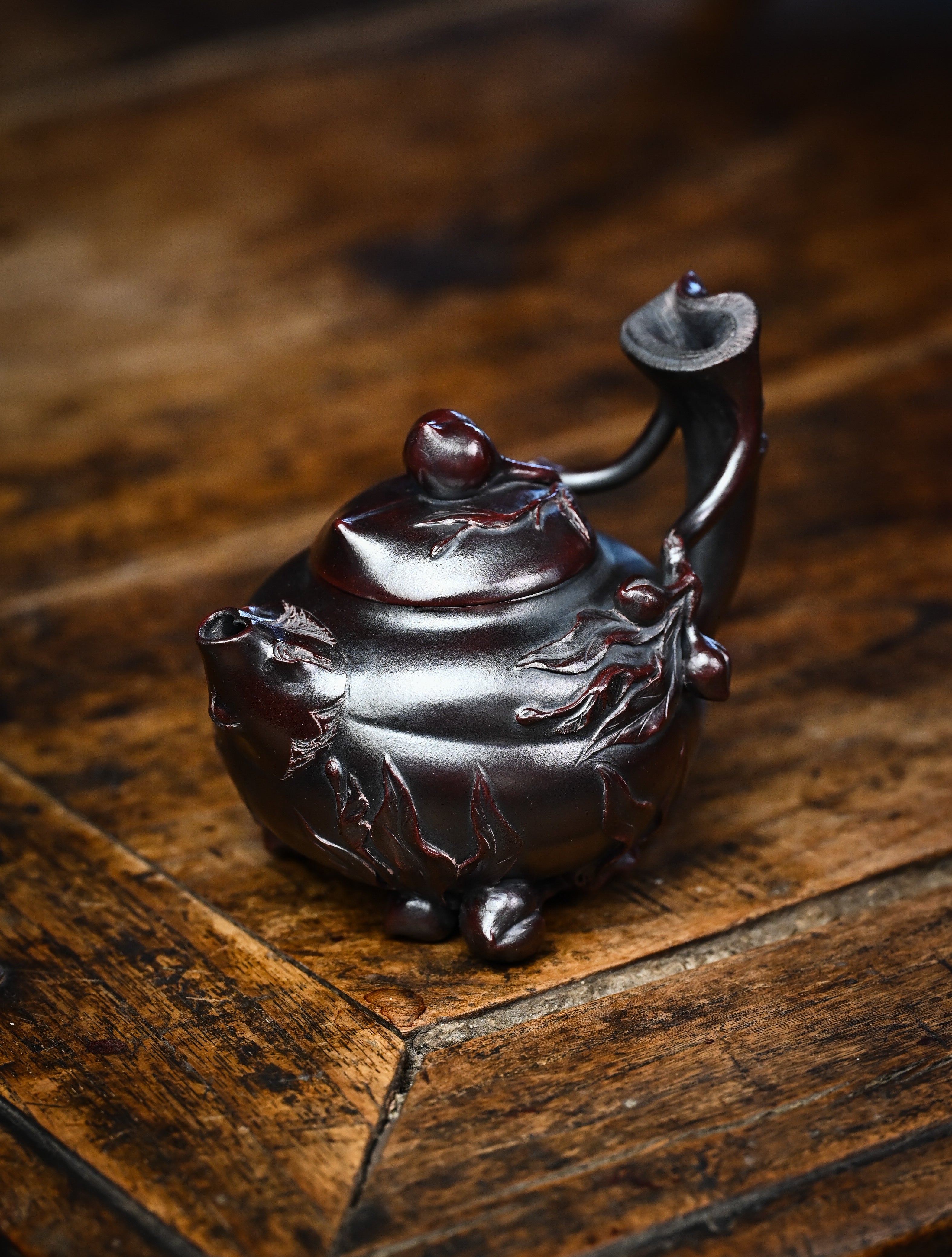 YANYOO handmade Yixing teapot featuring aged Wuni clay and peach sculpture, lifestyle left side.