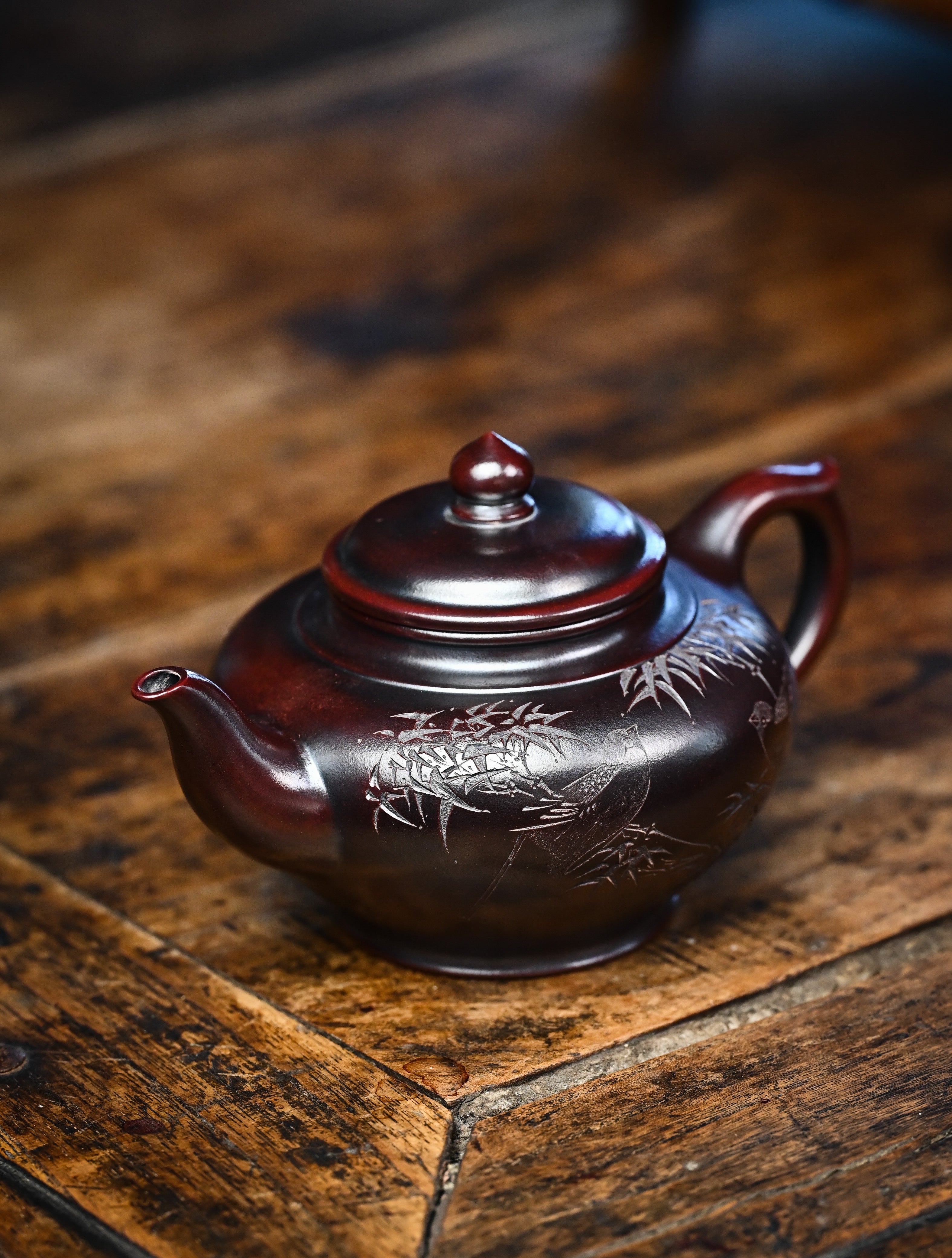 YANYOO handmade Yixing teapot featuring aged Wuni clay and bird engravings, lifestyle left side.