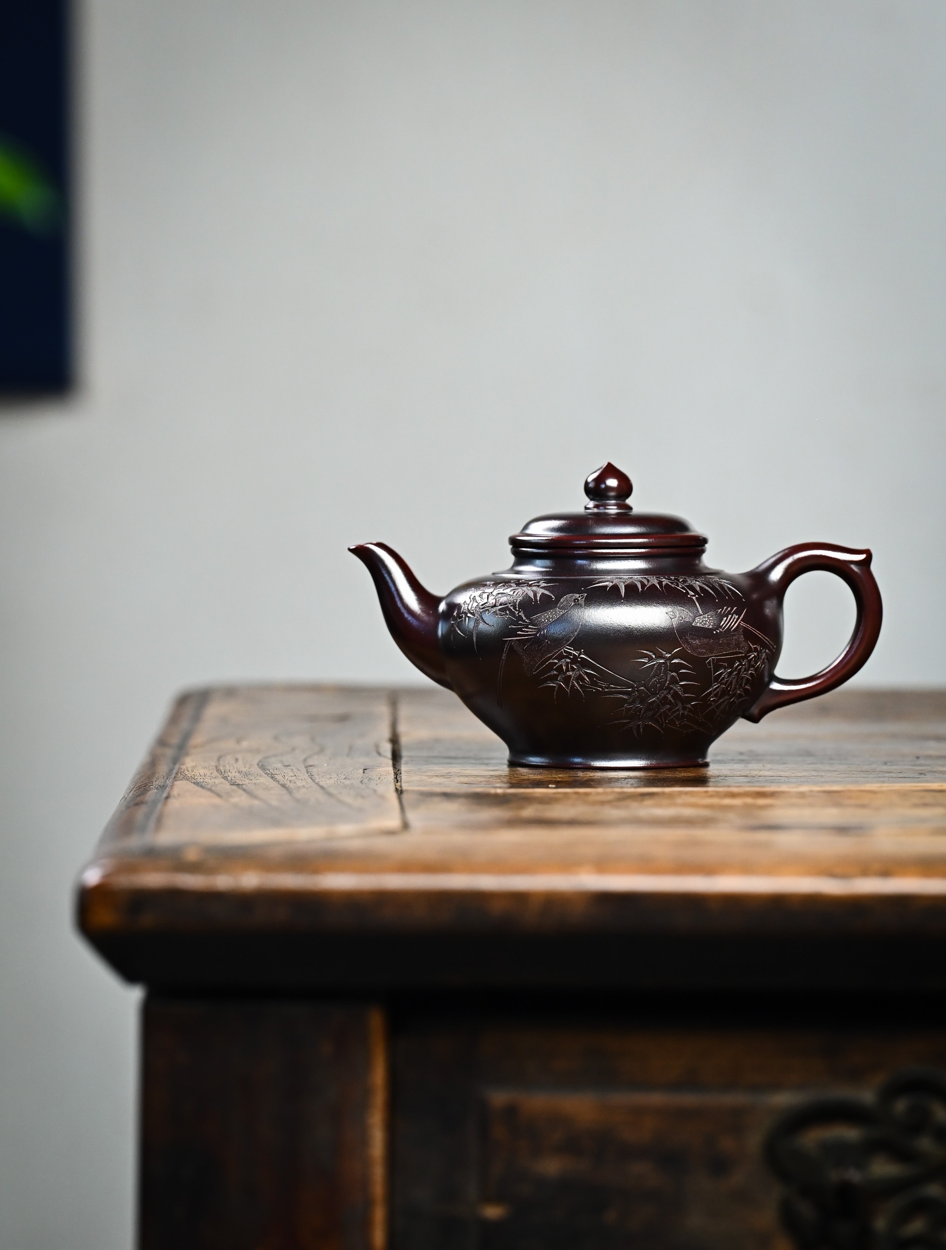 YANYOO handmade Yixing teapot featuring aged Wuni clay and bird engravings, lifestyle wide-angle left side.